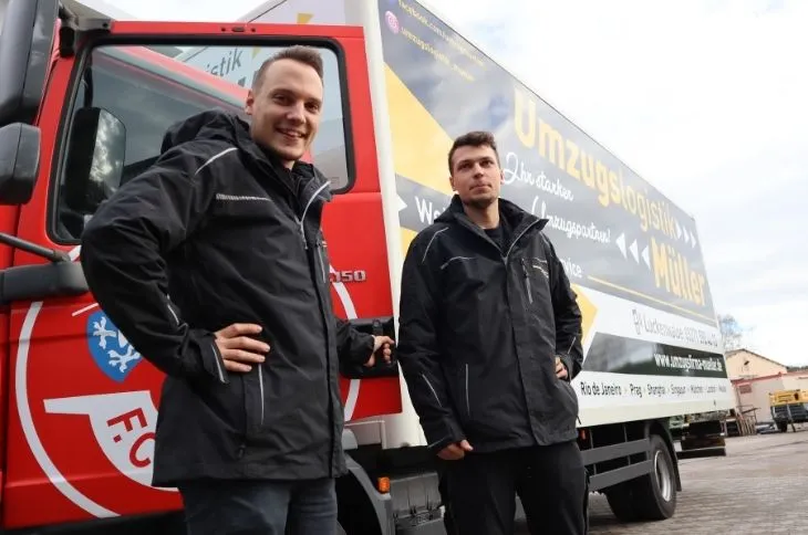 zwei umzugshelfer stehen vor umzugswagen